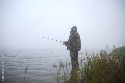 fisherman stands in the water on the lake. fisherman knee-deep in water in fog