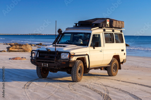 Western Australia – Outback adventure with 4WD vehicle at the beach of an ocean at sunrise with blue sky