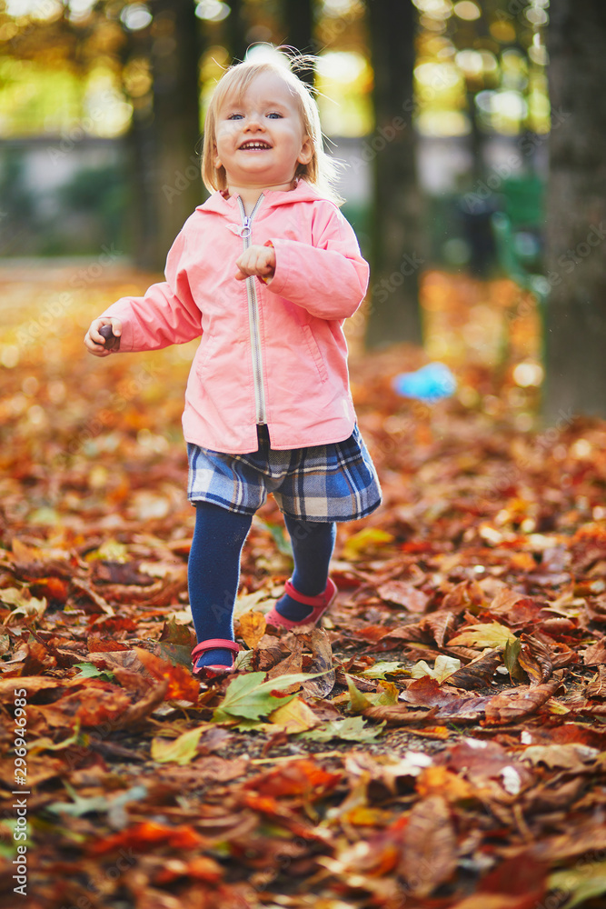 Adorable cheerful toddler girl running in Tuileries garden in Paris, France Adorable cheerful toddler girl running in Tuileries garden in Paris, France