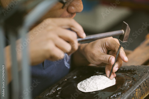 Silversmith using hammers and steel engraved  pattern on silver plate for accessory handmade photo