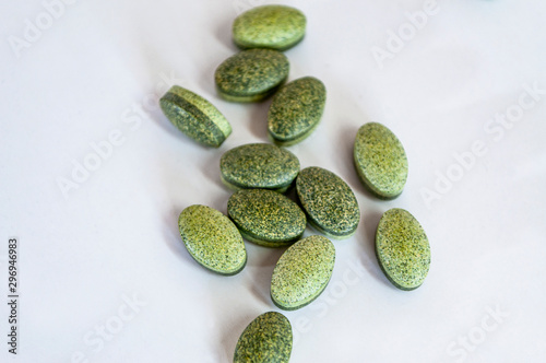 Top shoot of healthy green vitamin pills on white background