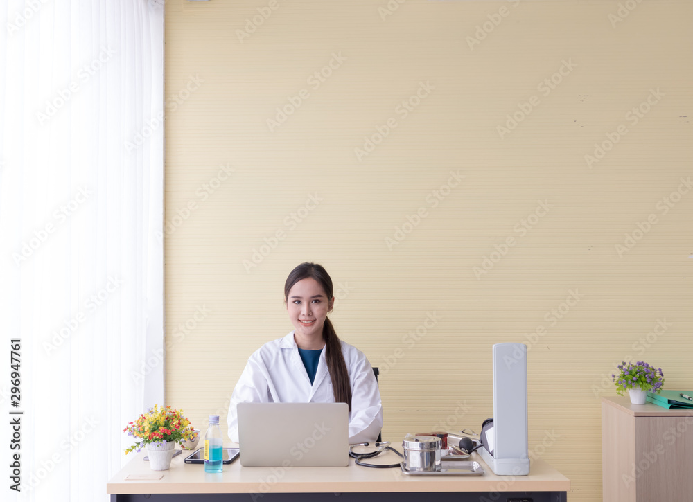 Asian female doctor sat with a computer and smiled happily.