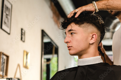 Fotografie Teenager getting a modern haircut in a vintage barber shop