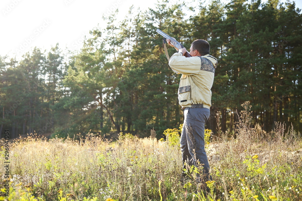 Naklejka premium hunter full length aiming a hunting rifle up in the forest in summer