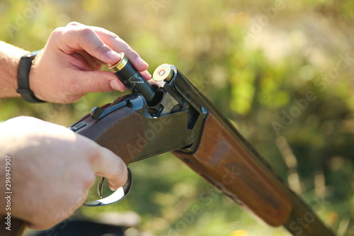 man’s hands loading a cartridge into a hunting rifle close up