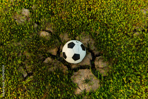 The football ball in a field that is dry and cracked in the evening sun