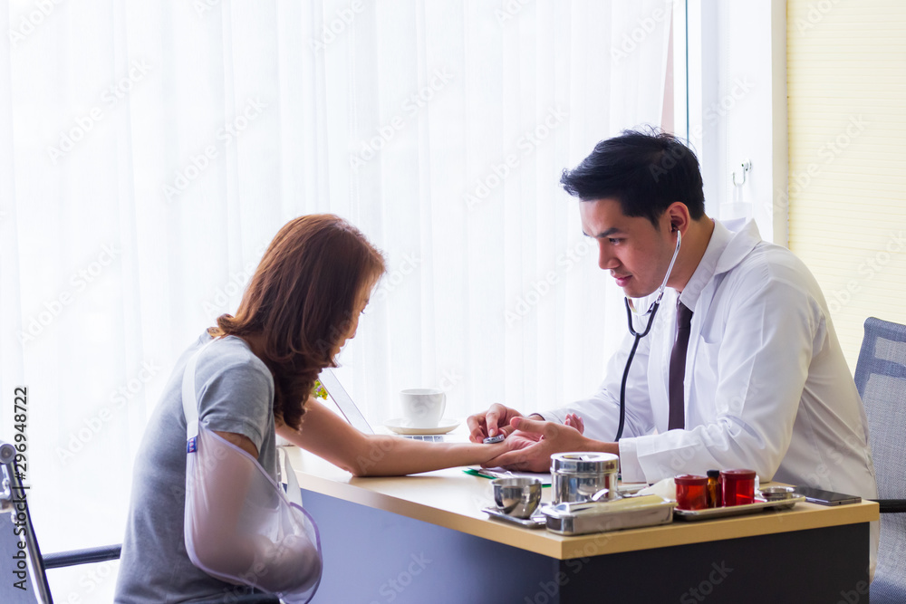 Fototapeta premium Male Asian doctor checked the patient's pulse to check the abnormalities of the heart on the desk