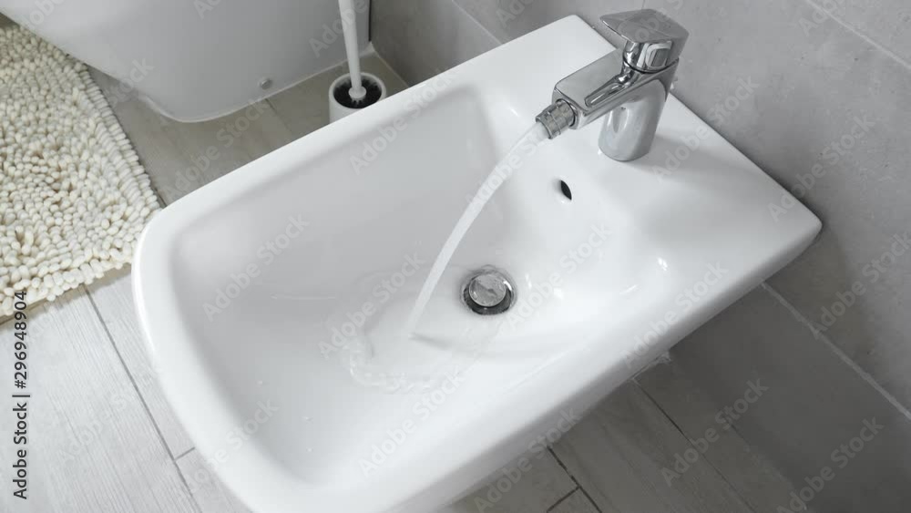 White ceramic bidet at modern toilet interior. Water is running. Nobody White ceramic bidet at modern toilet interior. Water is running. Nobody