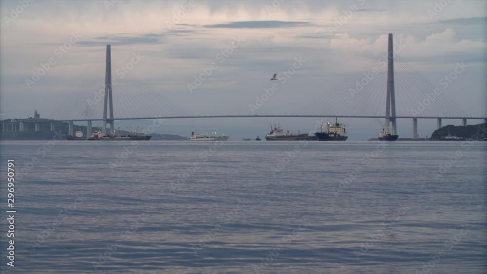 Static view of cable-stayed Russian bridge in early morning. Silhouetts of ships. Vladivostok, Russia Static view of cable-stayed Russian bridge in early morning. Silhouetts of ships. Vladivostok, Russia