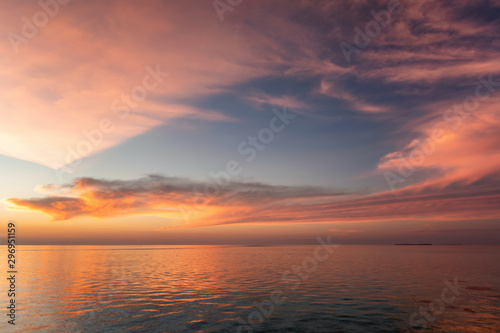 Tropischer Himmel über dem Meer bei Pastellrotem Sonnenuntergang