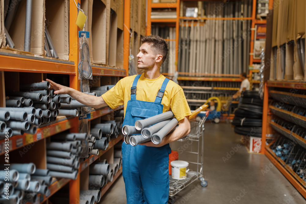 Male builder choosing piping in hardware store Male builder choosing piping in hardware store