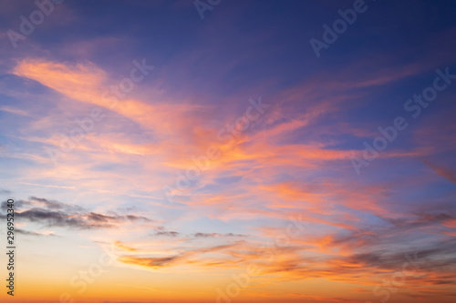Beautiful orange clouds on a golden blue sky during sunset. Scenic sundown cloudscape for background. Afterglow of sunset. © Maryia