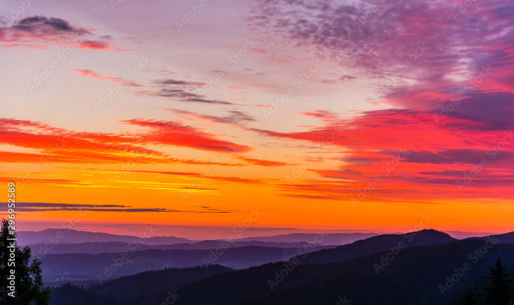 Beautifully the colors (orange, red, purple) of the sky at sunrise over the mountains and valleys.
