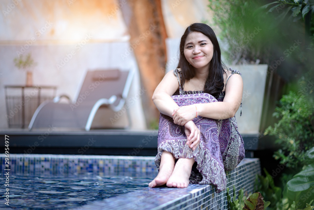 Asian women sit smiling happily At the edge of the pool at the hotel 