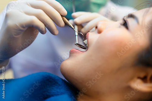 Dentist holding a dental tool of patients in the clinic.Woman lying on the dental chair for dentist checkup.
