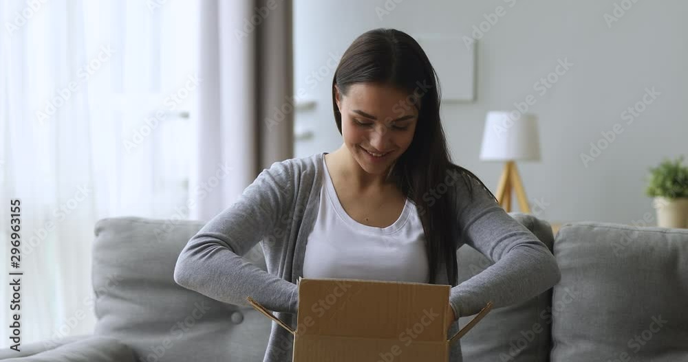 Satisfied female customer open parcel box sit on sofa Satisfied female customer open parcel box sit on sofa