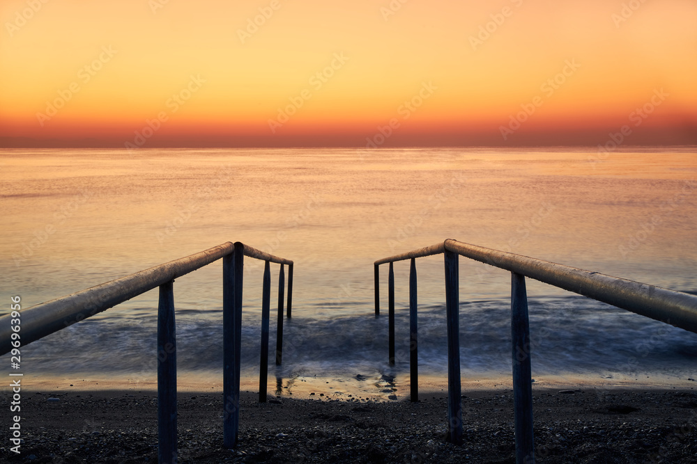 Ladder to enter the sea on the beach and a beautiful sunrise at sea
