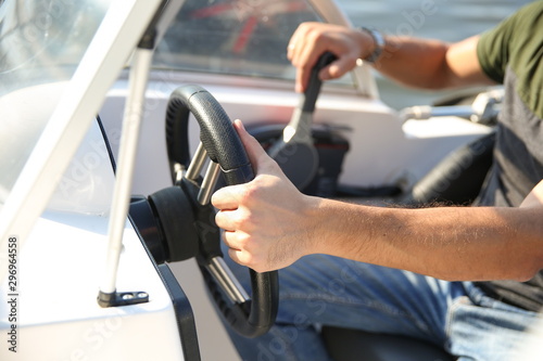 male hand is on a steering wheel of a white motor boat close up