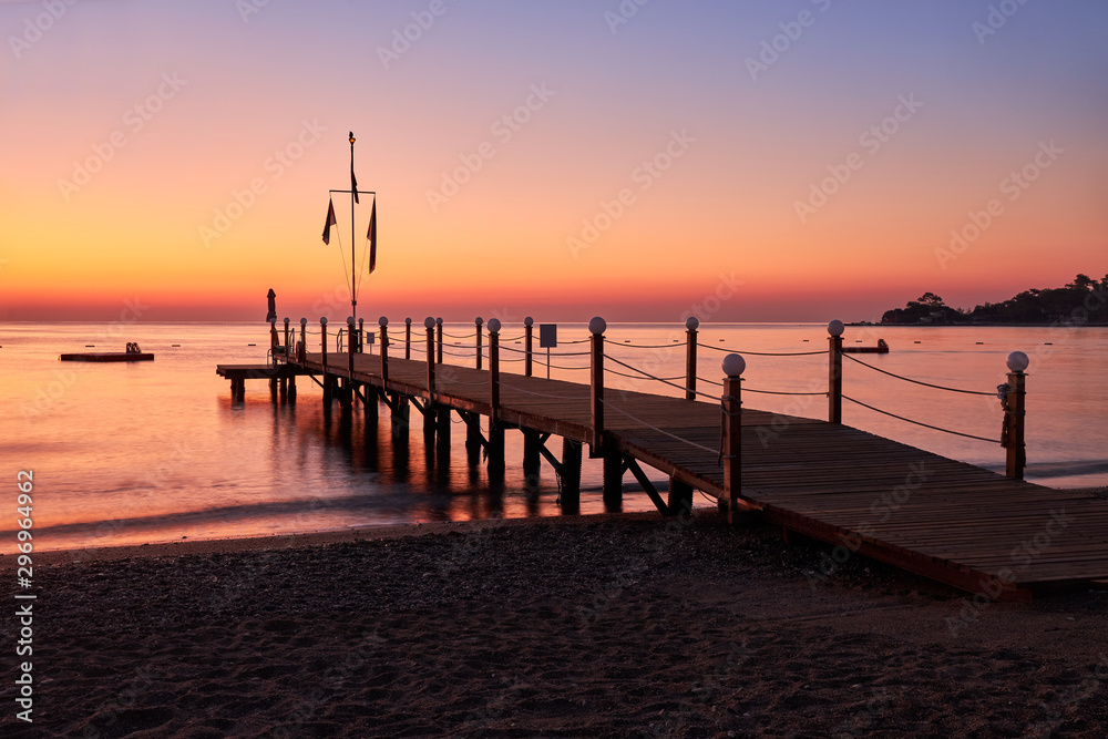 Sea dawn overlooking a large wooden pier and swimming pontoon.