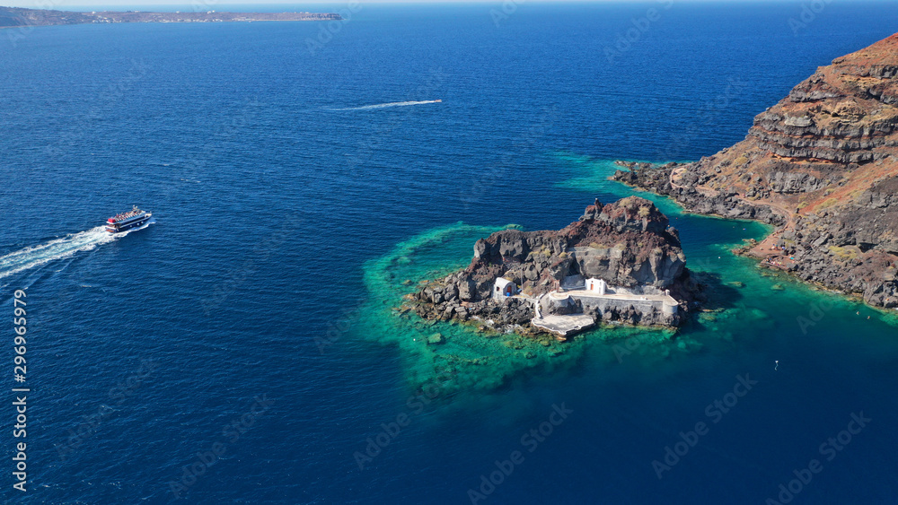 Aerial drone photo of picturesque volcanic with black rock islet and chapel of Agios Nikolaos in bay of Amoudi below iconic village of Oia, Santorini island, Cyclades, Greece