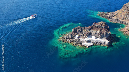 Aerial drone photo of picturesque volcanic with black rock islet and chapel of Agios Nikolaos in bay of Amoudi below iconic village of Oia, Santorini island, Cyclades, Greece
