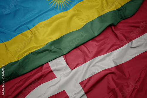 waving colorful flag of denmark and national flag of rwanda.