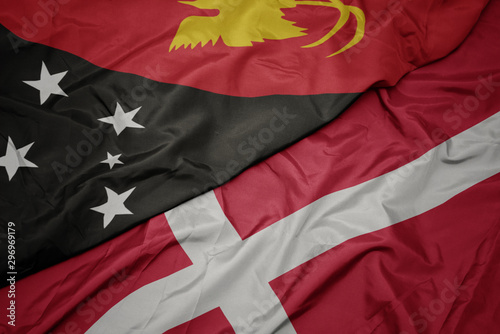 waving colorful flag of denmark and national flag of Papua New Guinea .