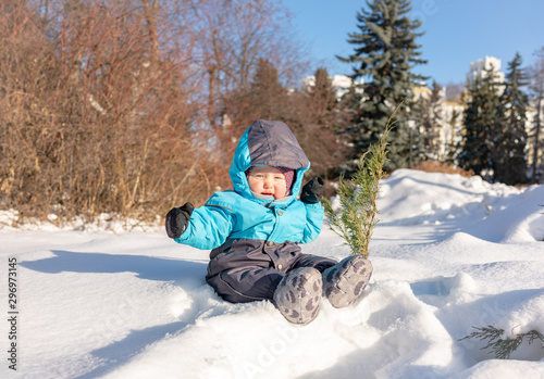 A small child sits in the snow at park