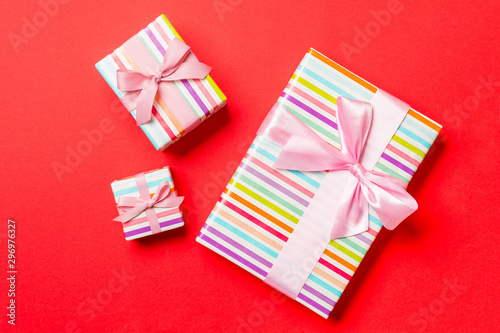 Gift box with pink bow for Christmas or New Year day on red background, top view