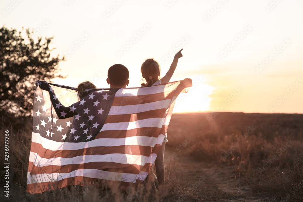Fototapeta premium A happy family with an American flag at sunset.