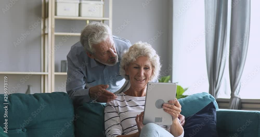 Smiling old couple talking using tablet computer at home Smiling old couple talking using tablet computer at home