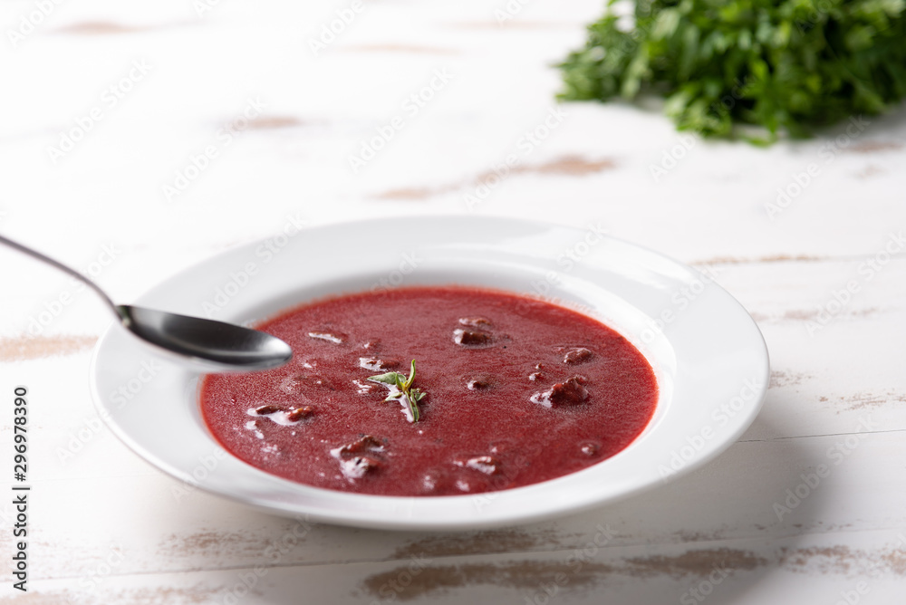 Delicious beet soup with sour cream in a white plate on white wooden table background. Soft light. Traditional Ukrainian Russian borscht beetroot soup Delicious beet soup with sour cream in a white plate on white wooden table background. Soft light. Traditional Ukrainian Russian borscht beetroot soup