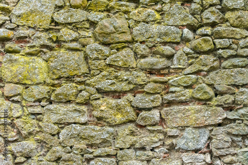 Aged or yellow stones wall of fortress cover with moss. Ancient stones background