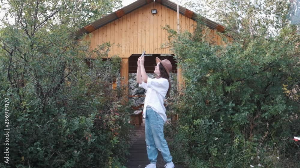 Attractive brunette in a hat takes a selfie on a cell phone, enjoys nature in the mountains Attractive brunette in a hat takes a selfie on a cell phone, enjoys nature in the mountains