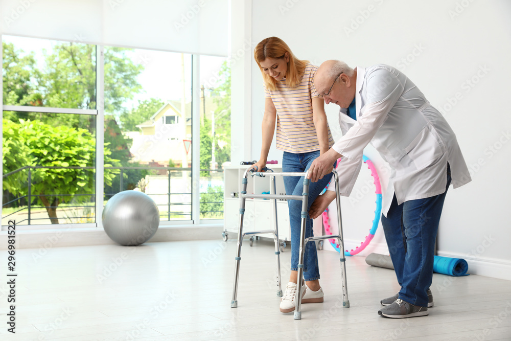 Doctor helping woman with walking frame indoors Doctor helping woman with walking frame indoors