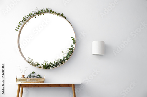 Round mirror and table with accessories near white wall in modern room interior photo