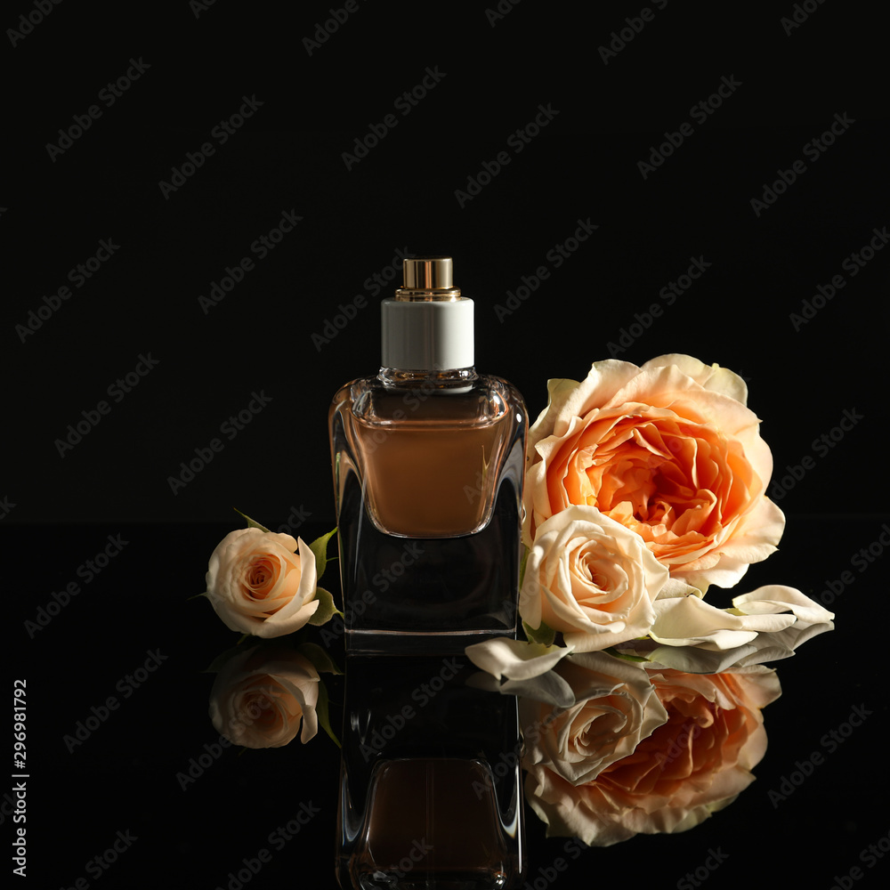 Elegant bottle of perfume and beautiful flowers on black background foto de  Stock | Adobe Stock