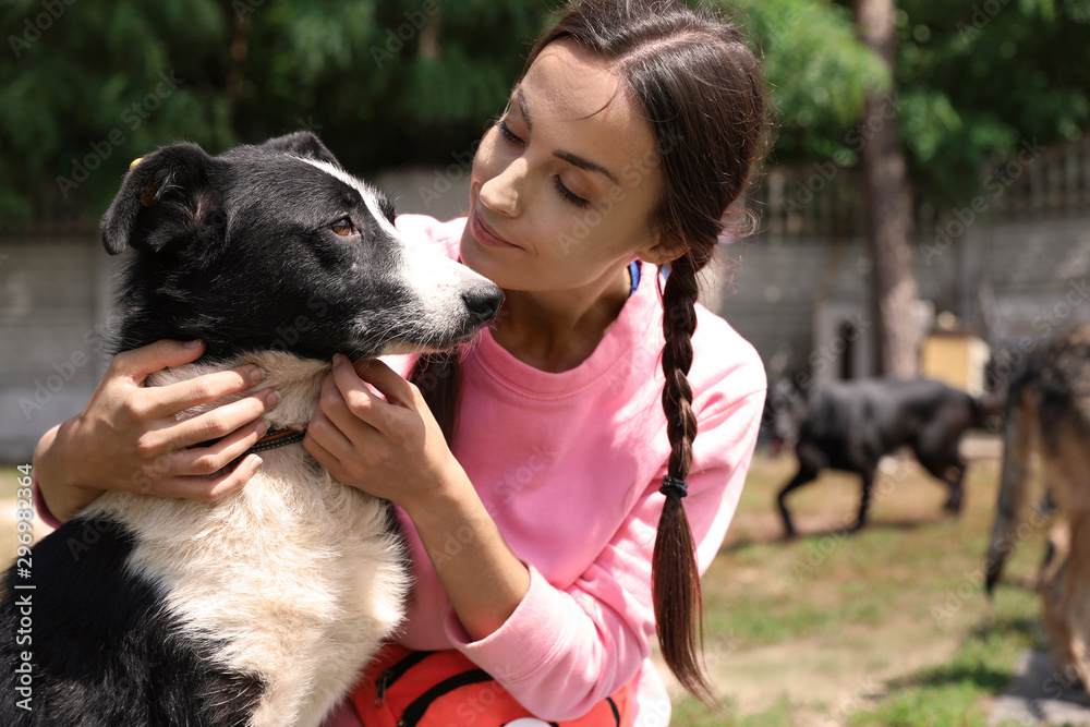 Female volunteer with homeless dog at animal shelter outdoors Female volunteer with homeless dog at animal shelter outdoors