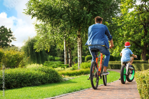 Fototapeta Naklejka Na Ścianę i Meble -  Dad and son riding modern bicycles outdoors