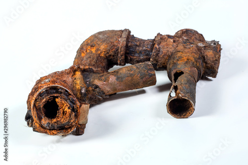 Fragments of old cast-iron water pipes on white background. After many years of operation corroded metal pipe was destroyed. Rusty steel tube with holes of metallic corrosion. Rusty cast iron, metal