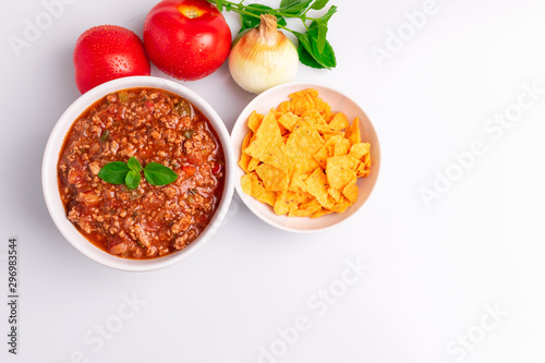 Bolognese (also know as Bolognesa or Bolonhesa) sauce and corn chips nachos in a white bowl isolated in white background, soft light, studio photo, copy space