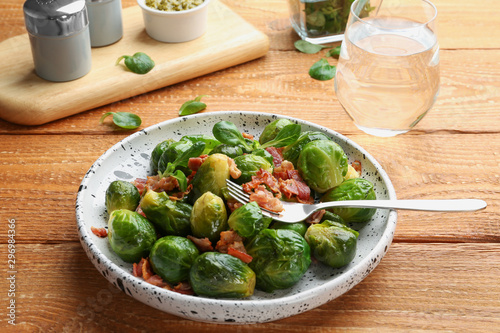 Tasty roasted Brussels sprouts with bacon on wooden table