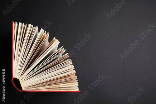 Hardcover book on black background, top view. Space for text