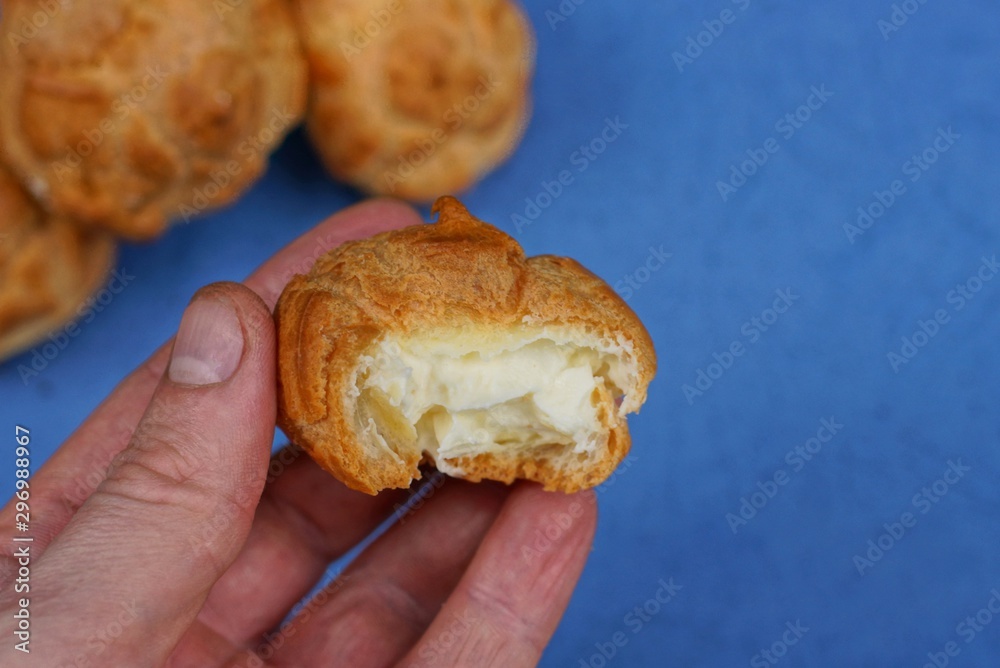 fingers holding a piece of brown donut with white cream fingers holding a piece of brown donut with white cream