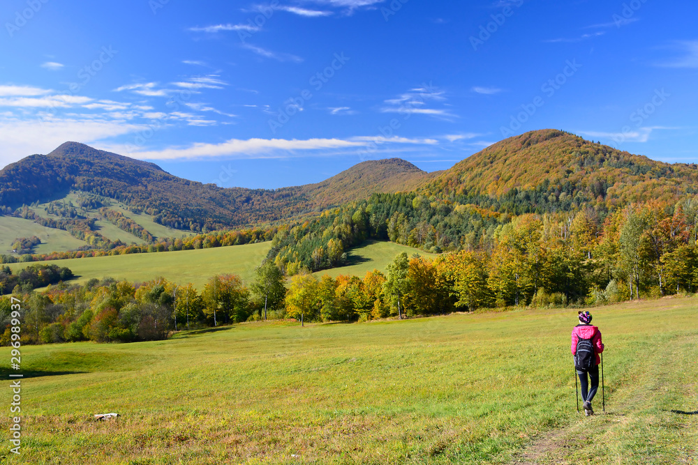 Woman backpacker on hiking trail in the mountains in autumn sunny day, Low Beskids (Beskid Niski)
