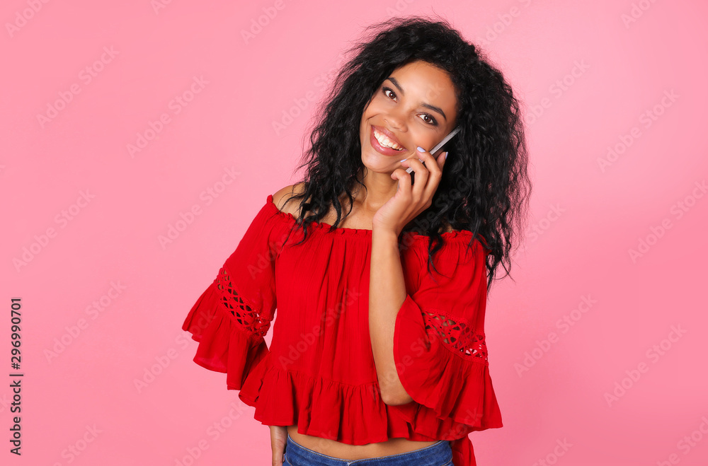 Hello, friend! Incredible African American woman in a red blouse and blue jeans is posing with her right hand on her hip and left hand holding a smartphone near her ear. Hello, friend! Incredible African American woman in a red blouse and blue jeans is posing with her right hand on her hip and left hand holding a smartphone near her ear.