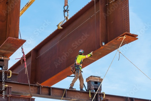 Tableau sur toile Steel worker positioning a steel girder with 3 meter wide flange on temporary supports to bolt in the next section of bridge girder