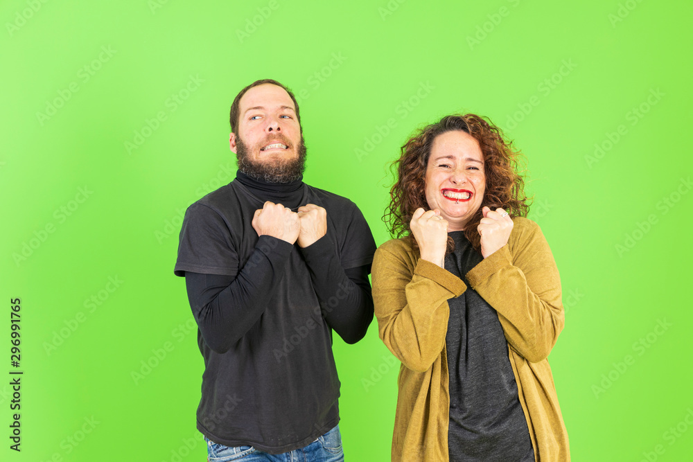 Beautiful young couple over green background celebrating surprised and amazed for success with arms raised. Winner concept.