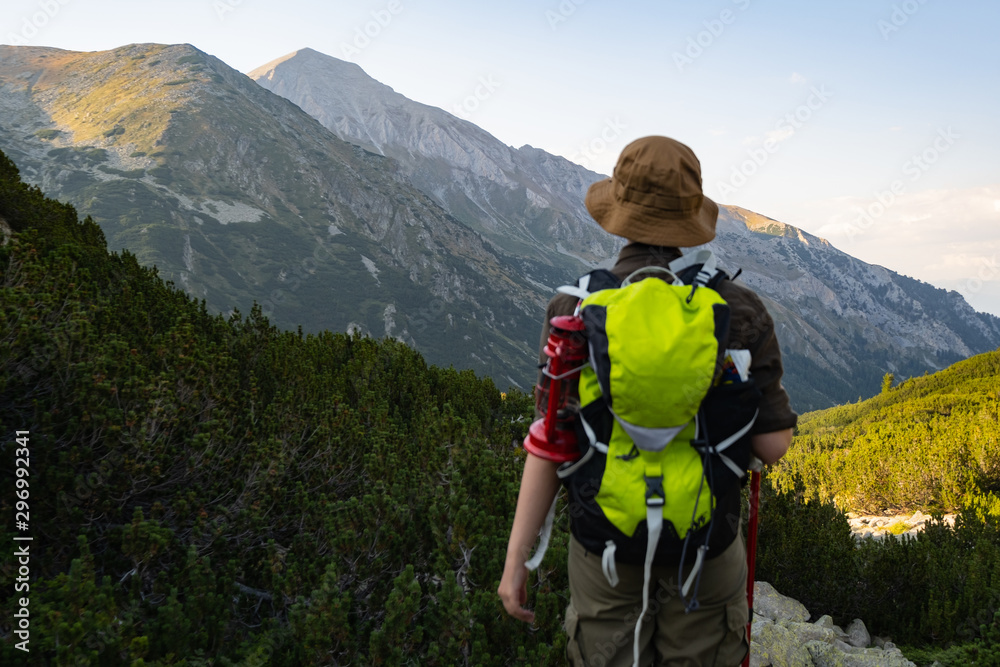Young happy female with backpack and gas lantern stand in the beautiful mountains Young happy female with backpack and gas lantern stand in the beautiful mountains