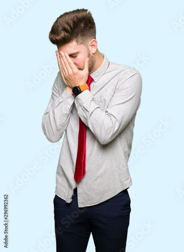 Young handsome business man with sad expression covering face with hands while crying. Depression concept.